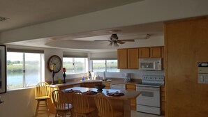 A spacious kitchen with a large island, wooden cabinets, a microwave, and a stove. - River Front guest house with Ramp, Beach, Volleyball, and Gazebo on the Water (Big River)