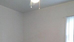 Ein Schlafzimmer mit Bett, Deckenventilator und Fenster.