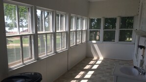 A kitchen with large windows, a sink, and a trash can.