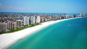 Un paysage urbain côtier avec une longue étendue de plage de sable blanc et un océan bleu limpide.
