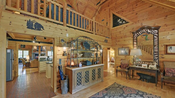 A log cabin interior with a kitchen, dining area, and a large mirror with a zebra print.