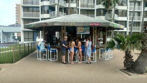 Un espace bar doté d’un coin salon abrité et d’un panneau publicitaire présentant différentes boissons.