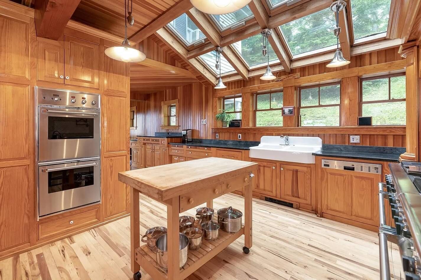 A spacious kitchen with wooden cabinets, a large island, stainless steel appliances, and a skylight.