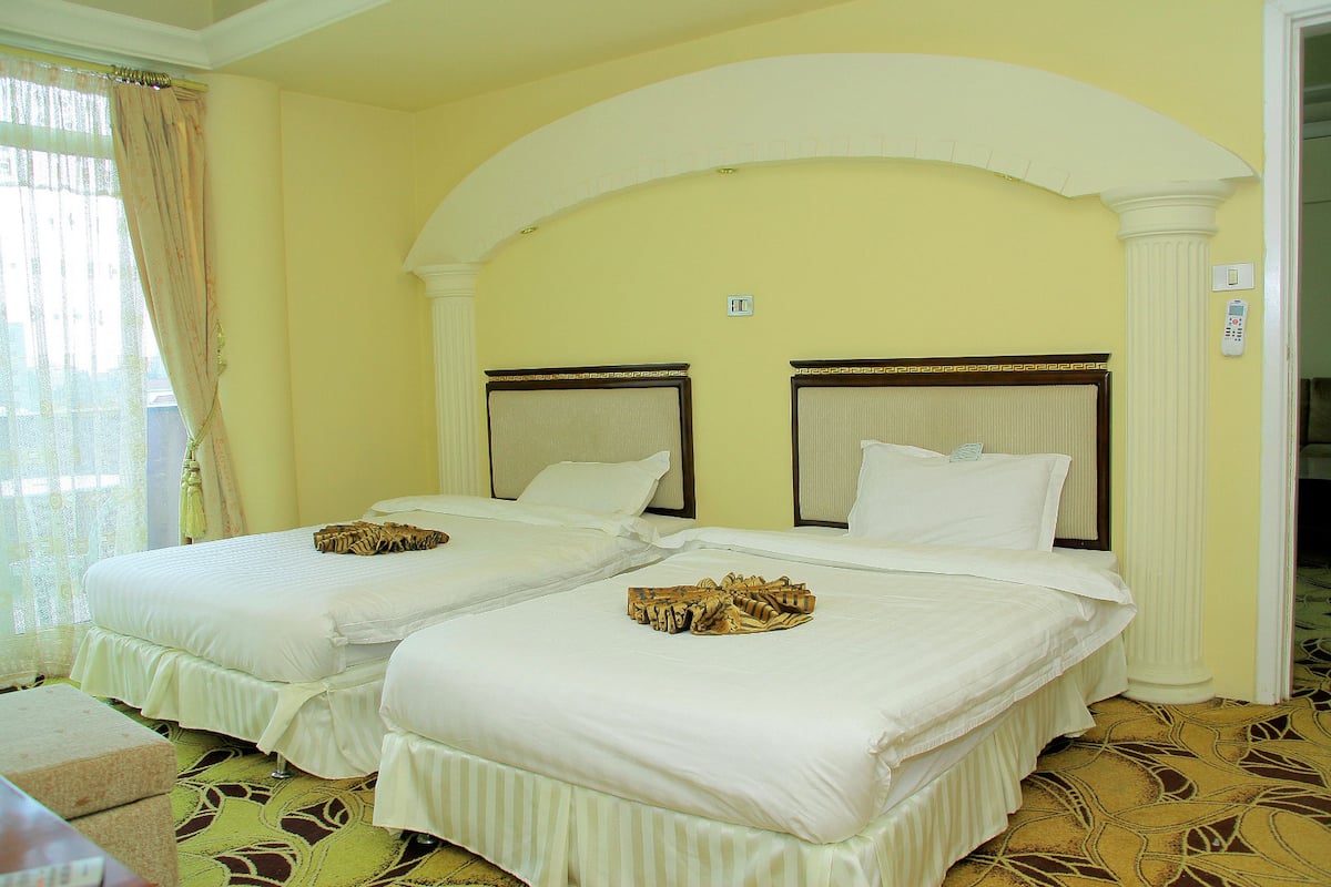 Habitación de hotel con dos camas, un amplio arco de entrada y una alfombra estampada.