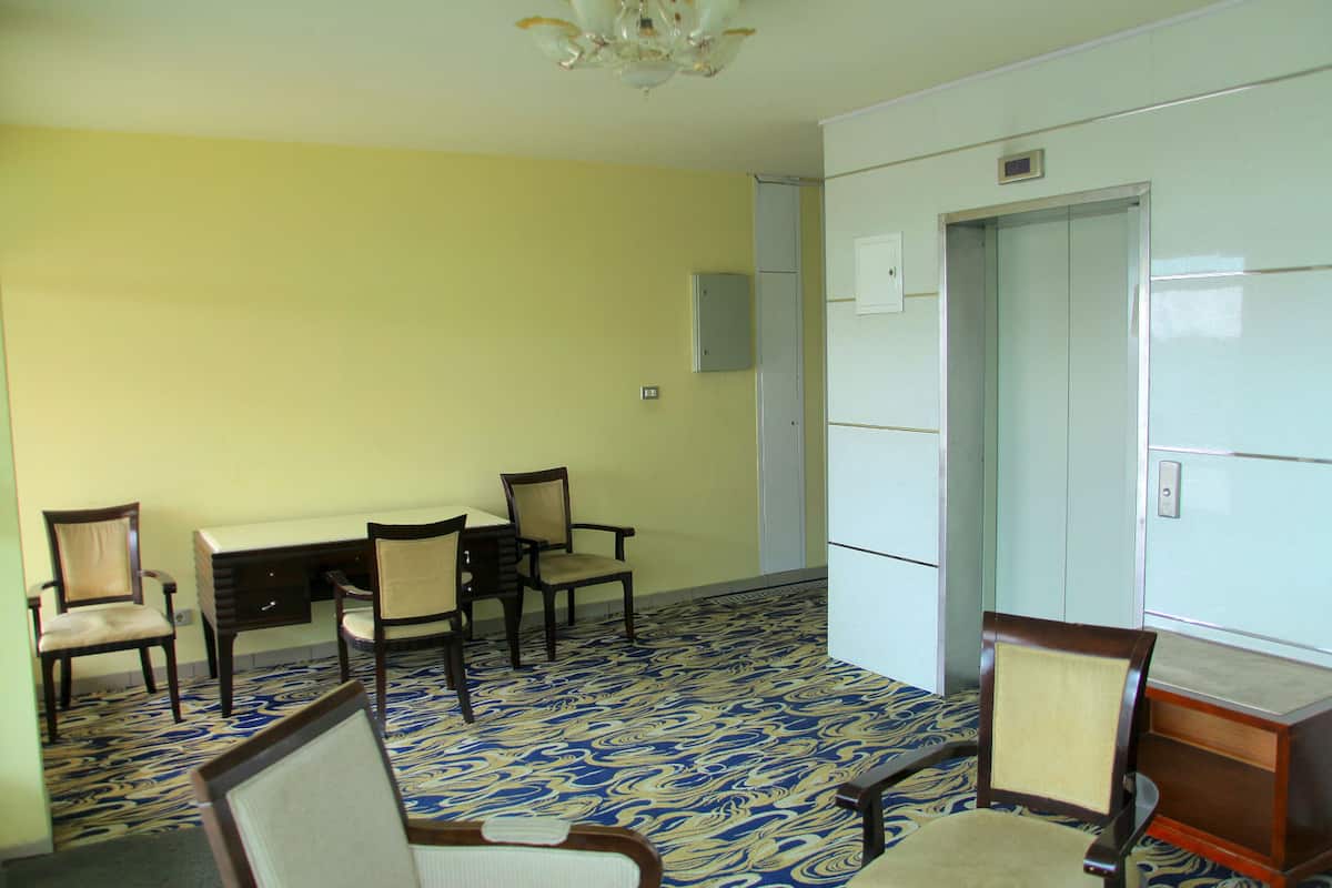 Una habitación con piso estampado, un escritorio, sillas y un armario.