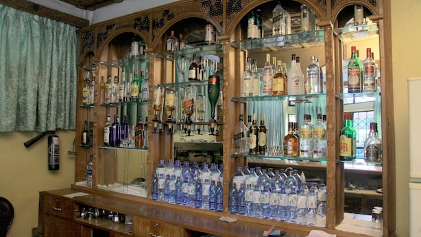 A bar area with shelves stocked with various liquor bottles and glasses. - Yonas Hotel (Addis Ababa)