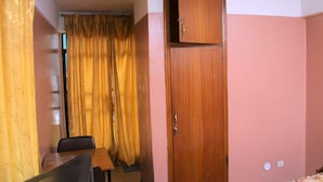 A room with a wooden wardrobe, a table, and a chair. - Yonas Hotel (Addis Ababa)
