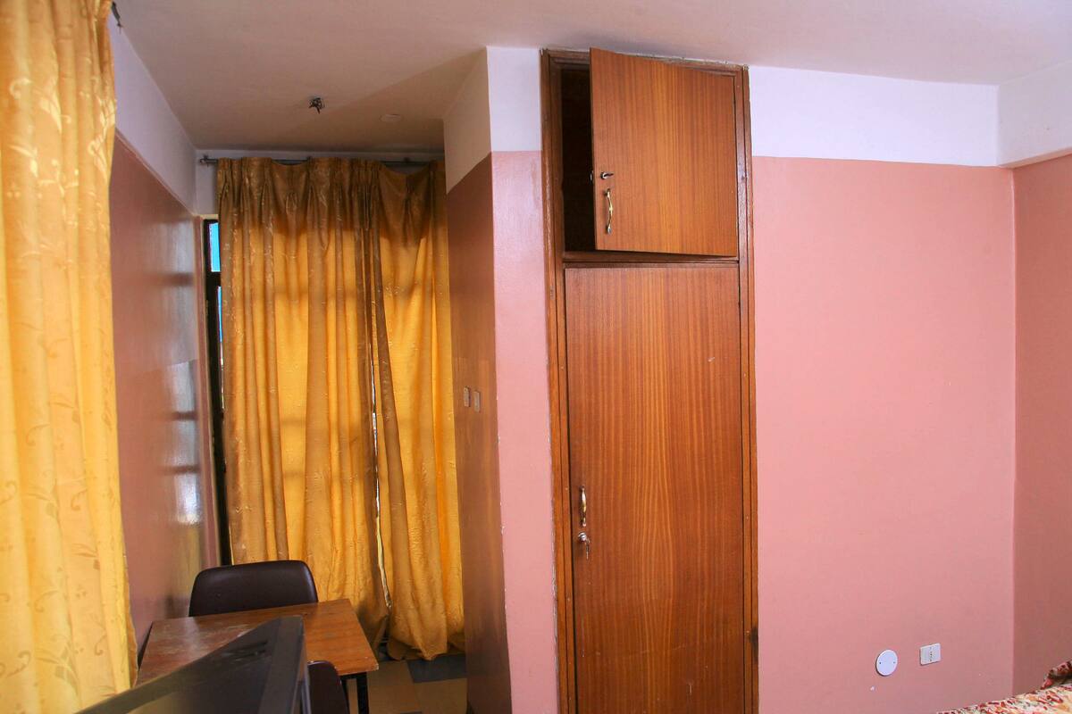 Una habitación con un armario de madera, una mesa y una silla.