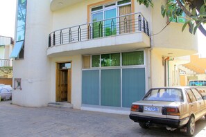 A two-story building with a balcony, a parked car, and a visible door. - Tseder Pension (Addis Ababa)