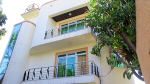A multi-story building with balconies, large windows, and a tree in the foreground. - Tseder Pension (Addis Ababa)