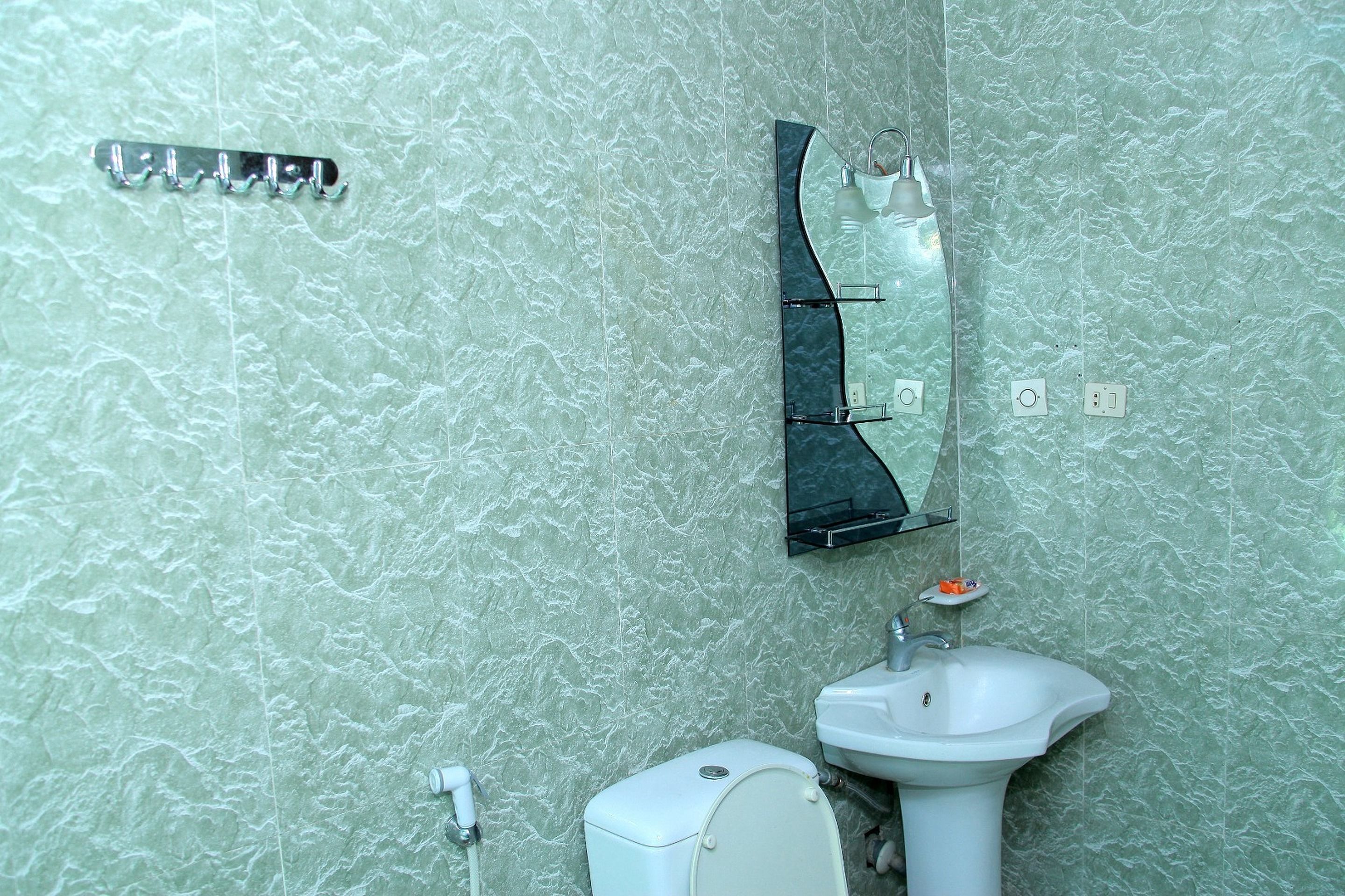 A bathroom with a toilet, sink, and a wall-mounted mirror.