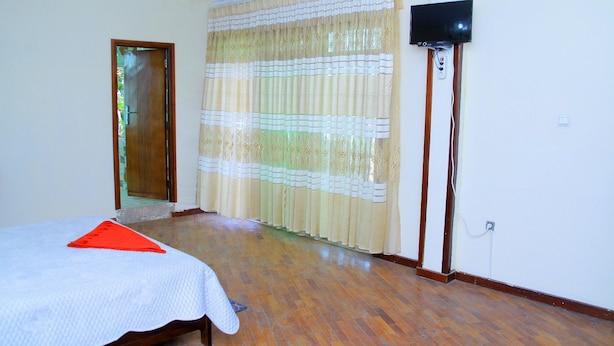 A bedroom with a bed, a television, and a window with curtains. - Tseder Pension (Addis Ababa)