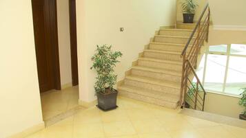 A staircase with a handrail, potted plants, and a light-colored tiled floor.