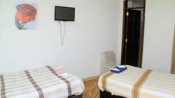 Une chambre avec deux lits, une télévision et une porte.