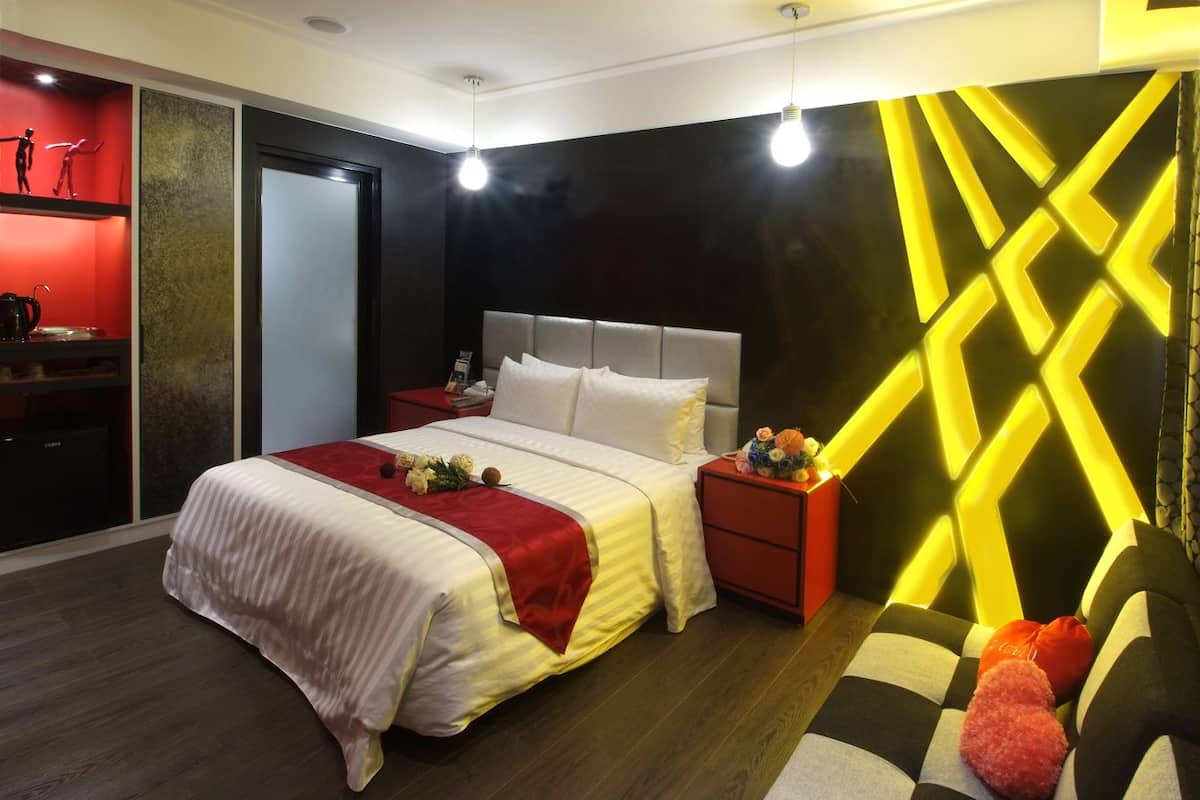 Une chambre d’hôtel moderne avec un grand lit, une table de chevet, un bureau rouge et un décor mural original.