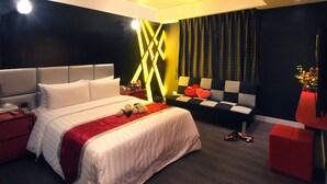 A modern hotel room with a large bed, a sofa, and a red ottoman. - Cai-Lai Hotel (Taoyuan City)