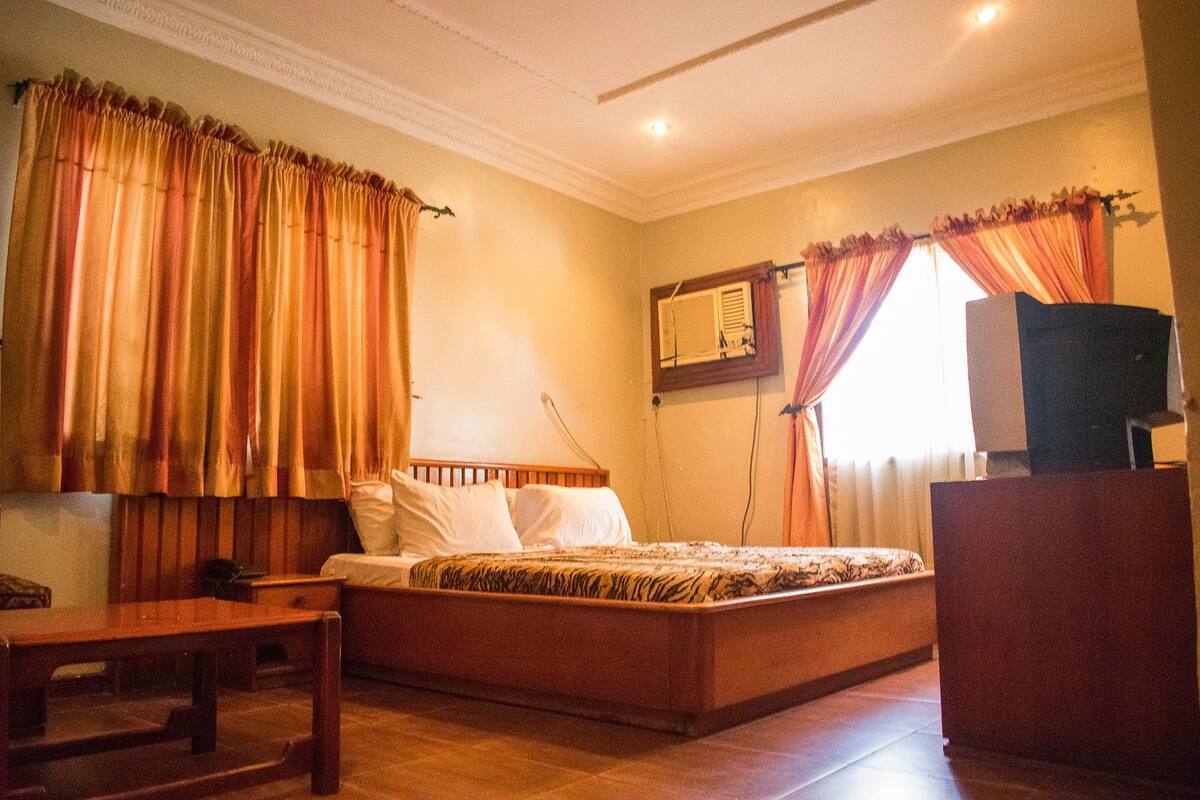 A bedroom with a wooden bed, a desk, and curtains.