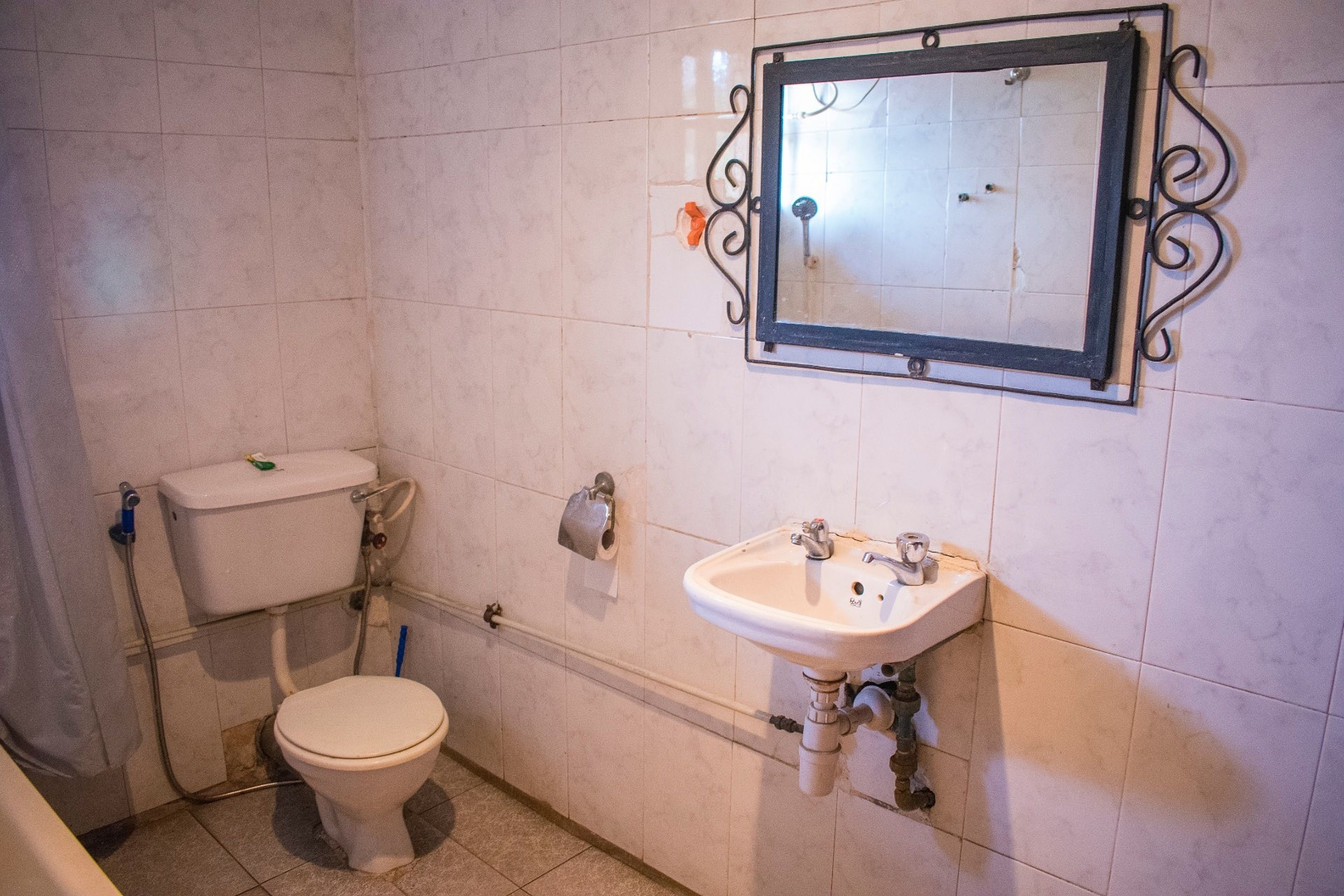 A bathroom with a toilet, sink, and mirror.