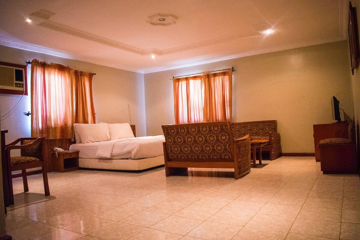 A hotel room with a bed, two sofas, a chair, and a small table.