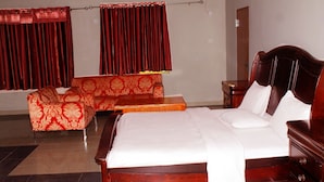 Une chambre d’hôtel avec un grand lit, un canapé, une petite table et des rideaux.