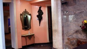 Un couloir doté d’un sol en marbre, d’un grand miroir, d’une petite table et d’un élément décoratif mural.
