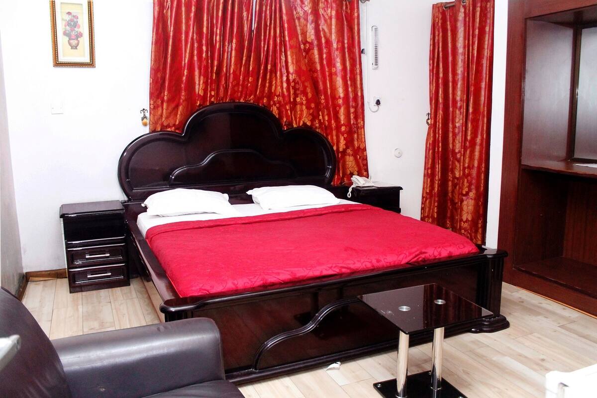 Un dormitorio ordenado con una cama de madera, una mesita de noche y una silla.