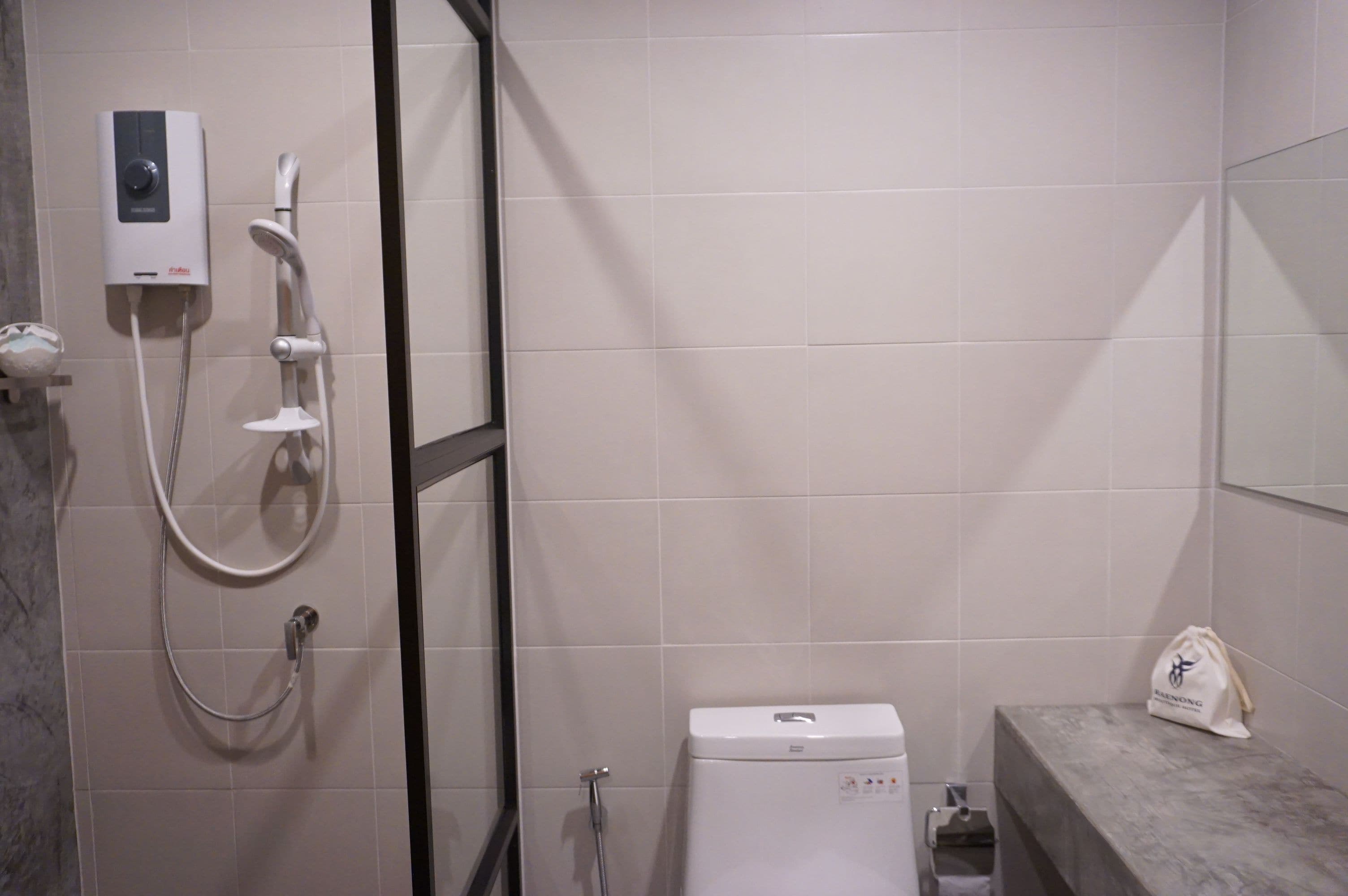 Een badkamer met een douche, toilet en een handdoekhouder.