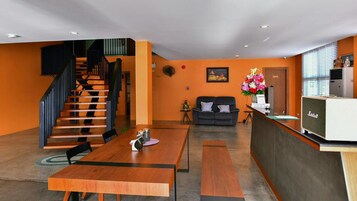 Un interior moderno con una escalera de madera, una zona de comedor, un sofá y una radio antigua.