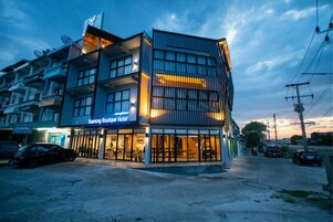 Un hotel con una fachada moderna, varios balcones y un cartel que indica que es el Hotel Boutique Raenong.