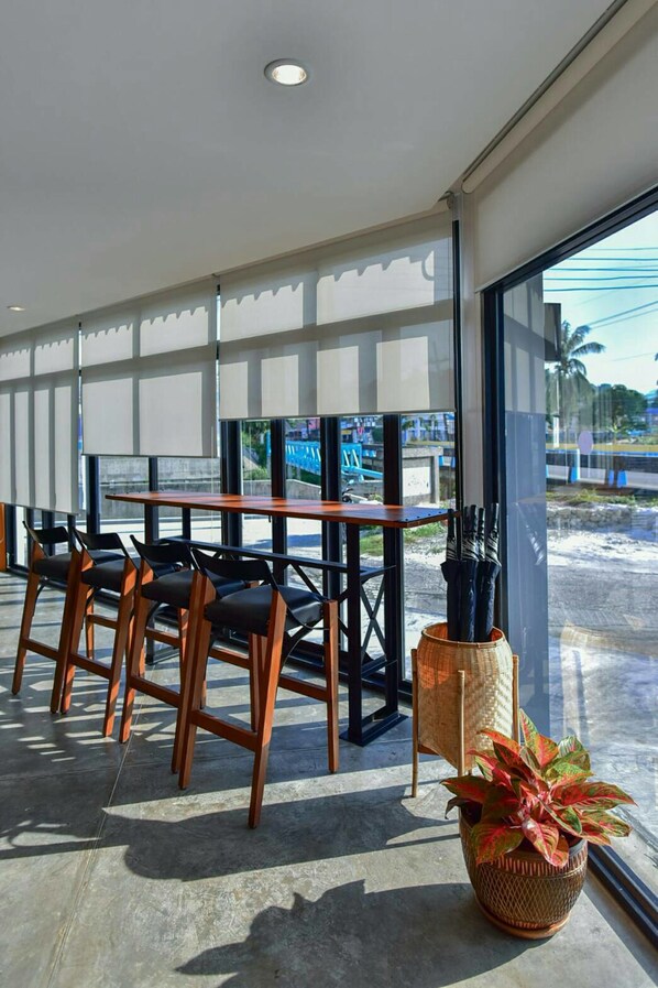 Un área de estar interior moderna con un gran ventanal, una mesa de madera y varias sillas.
