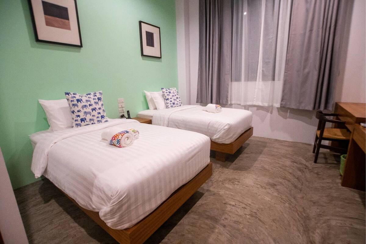 A hotel room with two beds, a desk, and a chair.