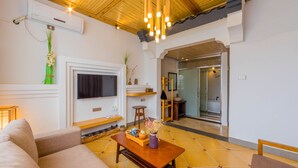 Una sala moderna con sofá, mesa de centro y televisor. Tiene techo de madera y piso de baldosas.