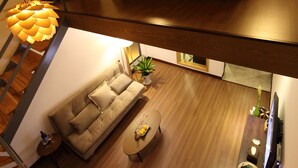 Un dormitorio estilo loft moderno con una cama grande, una escalera de madera y una zona de comedor con sofá y mesa de centro.