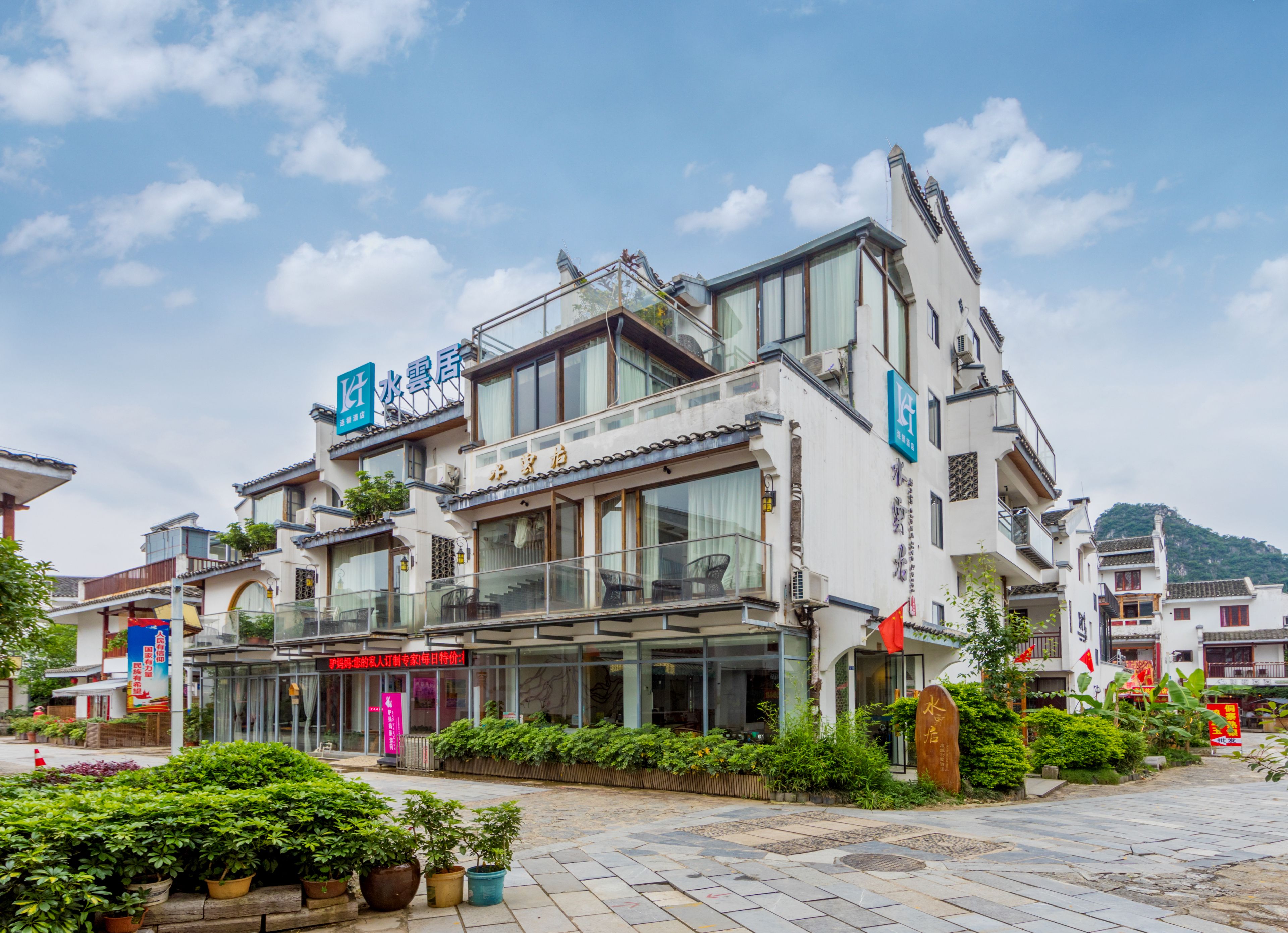 A modern hotel with a glass facade, multiple balconies, and a sign indicating it is a hotel.