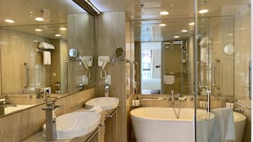 A modern bathroom with two sinks, a large bathtub, and a glass shower enclosure.