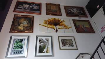 A wall with various framed artworks, including floral and abstract paintings.