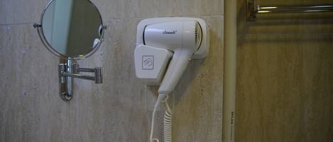A bathroom with a round mirror, a white hairdryer, and a towel rack.