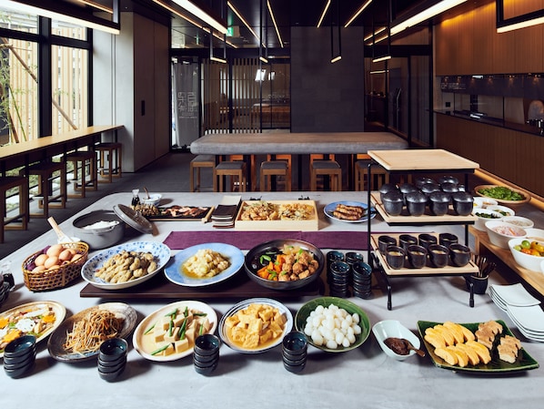 Un comedor amplio con una larga mesa dispuesta para una comida, que incluye diferentes platos y utensilios.