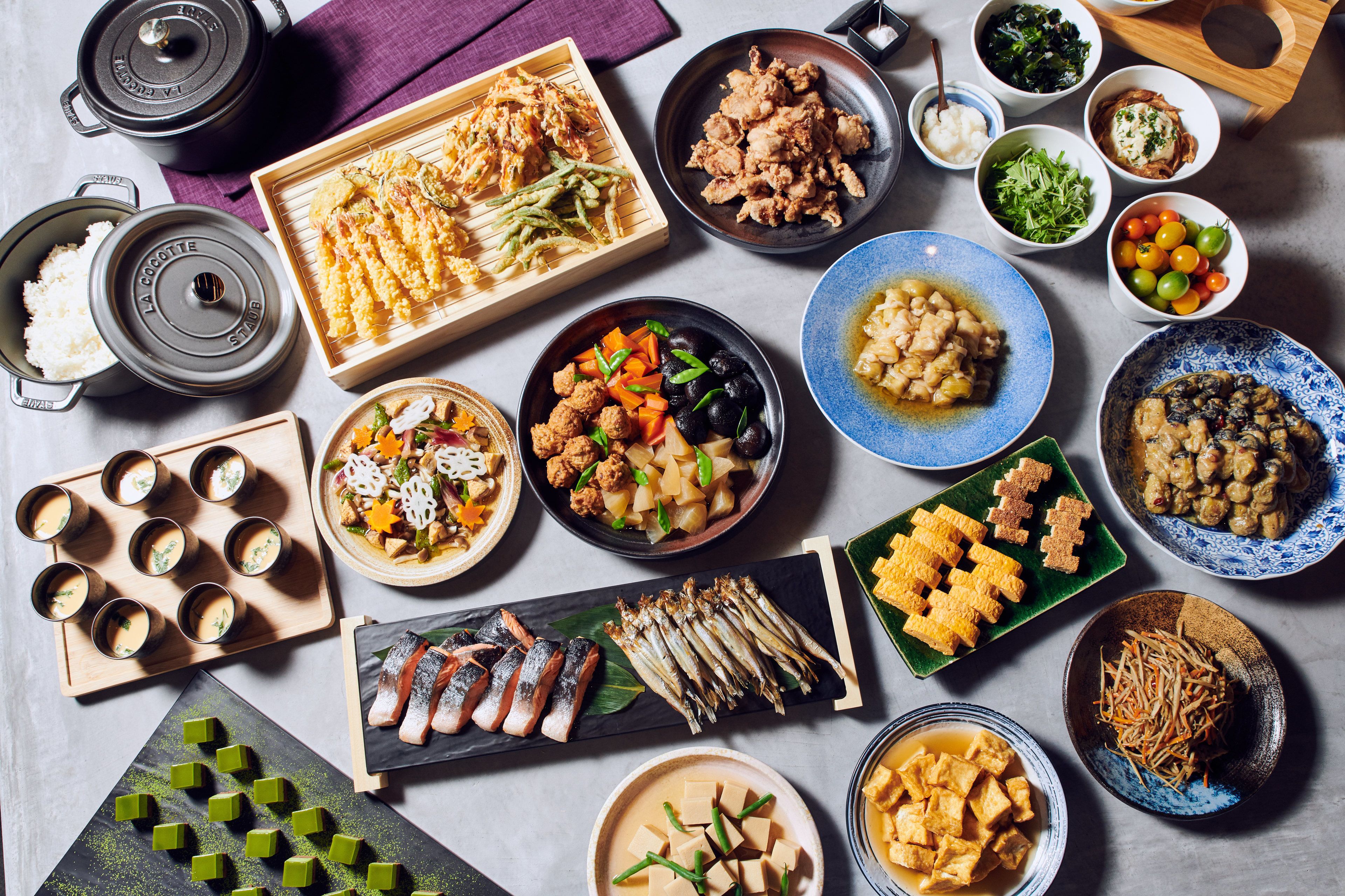 A variety of dishes including sushi, sashimi, and other Asian cuisine, arranged on a table.