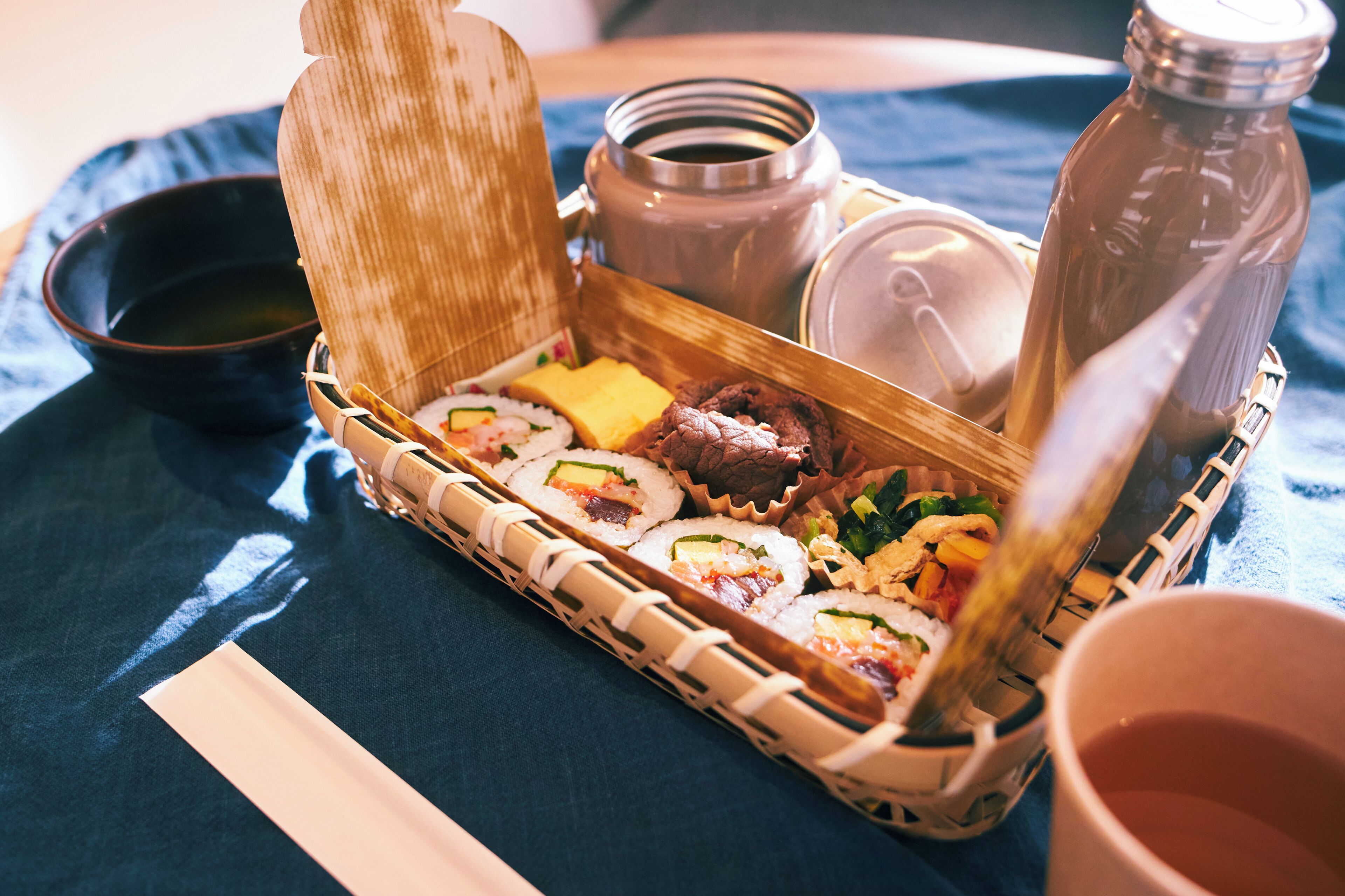 A sushi meal with a bamboo container, a bottle of soy sauce, and a small bowl of wasabi.