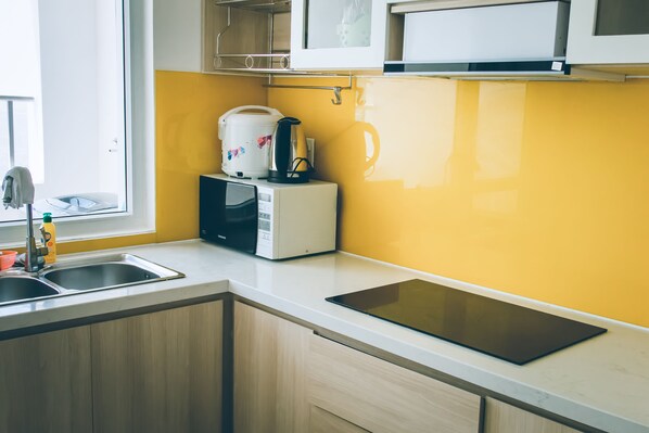 A modern kitchen with a yellow backsplash, a built-in microwave, a coffee maker, and a tablet on the counter.