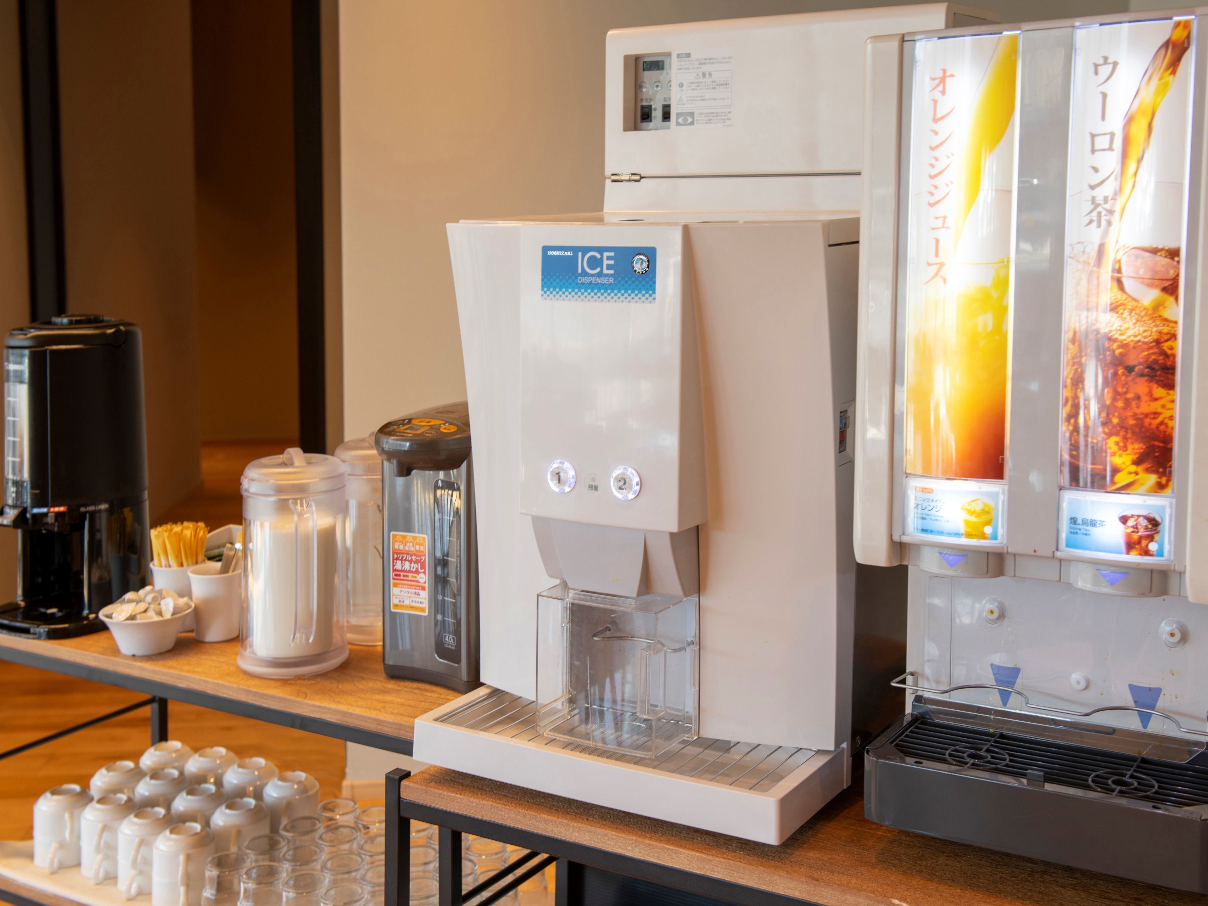 A coffee machine, a refrigerator, and a beverage dispenser on a counter.