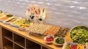 Une table de buffet garnie de divers plats et agrémentée d’une composition florale de fleurs blanches.