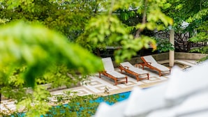 Un espace piscine avec des chaises longues et une petite statue.