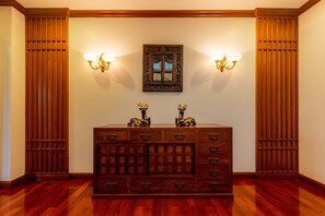 A wooden dresser with multiple drawers and two decorative animal figurines on top, flanked by two wall sconces with light fixtures. - Royal River Park (Bangkok)