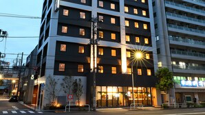 Un moderno edificio hotelero con varios pisos, ventanas iluminadas y una entrada visible.
