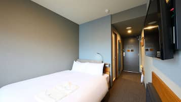 A hotel room with a large bed, a flat-screen TV mounted on the wall, and a carpeted hallway.