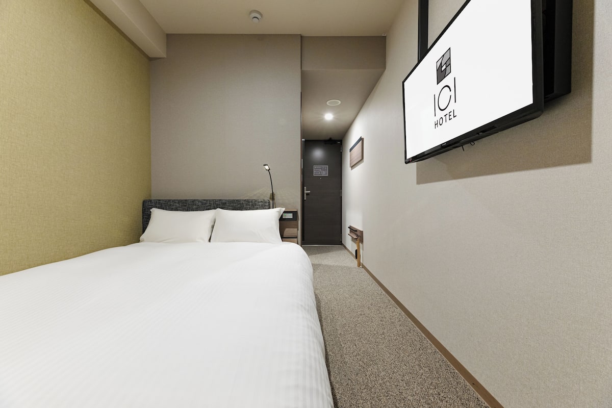 Een hotelkamer met een bed, nachtkastje, lamp en een bord aan de muur.