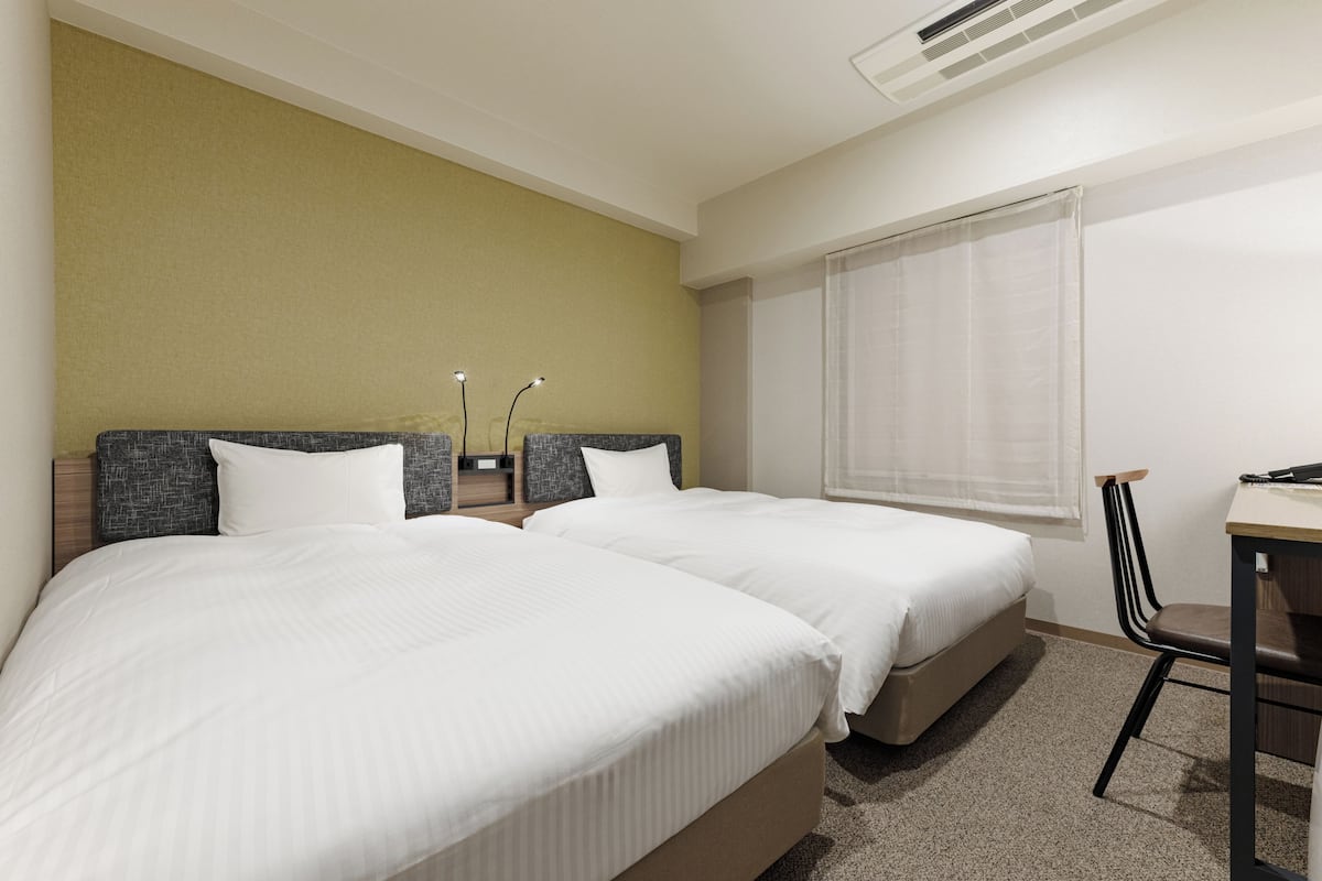 Een hotelkamer met twee bedden, een bureau en een stoel.