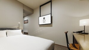 Una habitación de hotel con una cama grande, un escritorio con una silla, una lámpara y un cartel en la pared.
